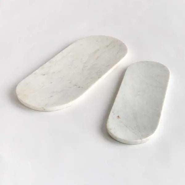 A set of two oval white marble trays, with a large and small tray displayed together, showcasing the unique natural veining in the stone.