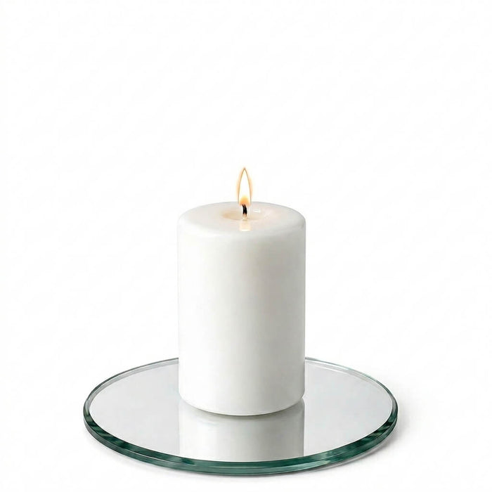 A 5" Round Mirror Coaster holding a lit white pillar candle isolated on a white background
