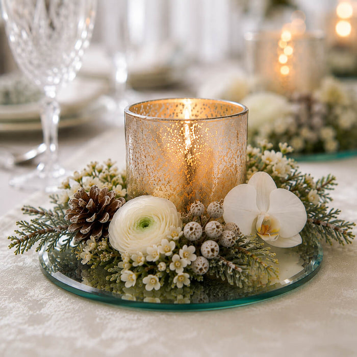Lit candle in a gold holder with flowers and a pinecone on a 5 inch round mirror tray