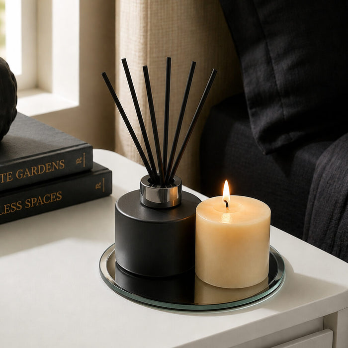 Reed diffuser and lit pillar candle on a 5 inch round mirror tray