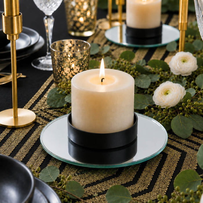 Lit pillar candle in a black holder on a 5 inch round mirror tray