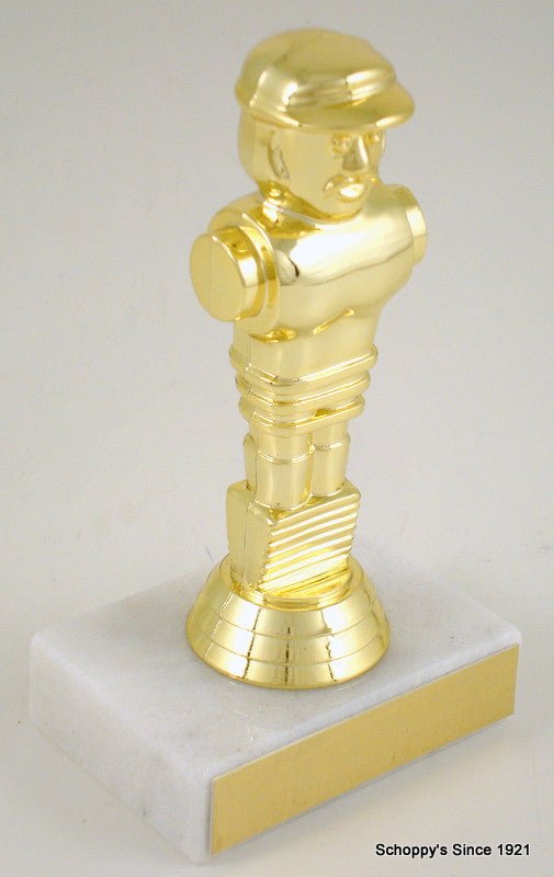 A shiny gold metallic figurine of a foosball figure mounted on a square white base with a gold front panel, photographed against a plain light background.