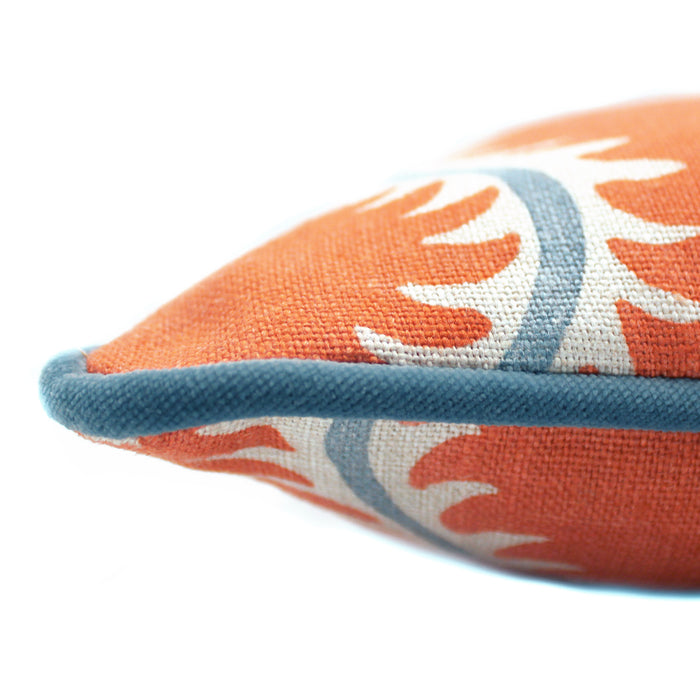 A orange, cream and blue linen cushion with a all-over repeat pattern and velvet piping.