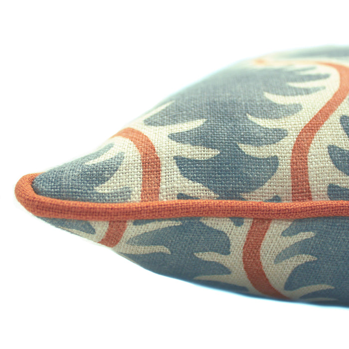 A blue, orange and cream linen cushion with a all-over repeat pattern and linen piping.