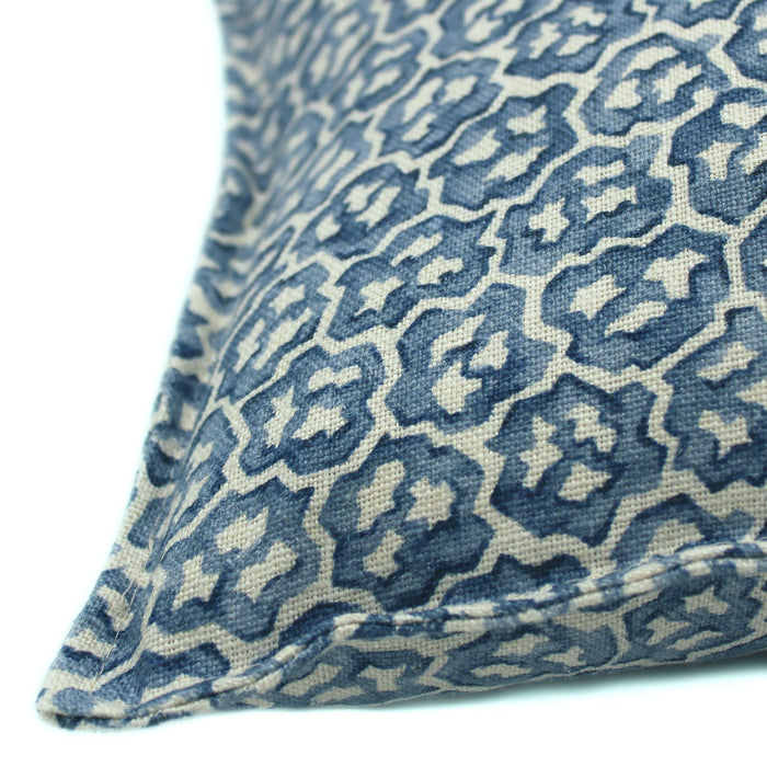 A blue and cream linen cushion with a block print pattern.