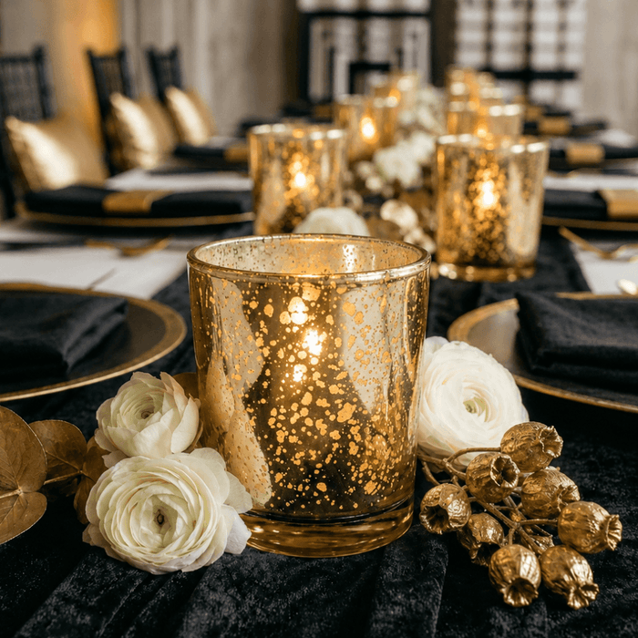 Amber Gold Mercury Votive Holder with lit candle on black tablecloth among white ranunculus flowers