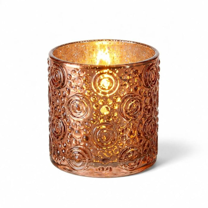 Rose gold mercury glass candle holder with glowing candle on white background