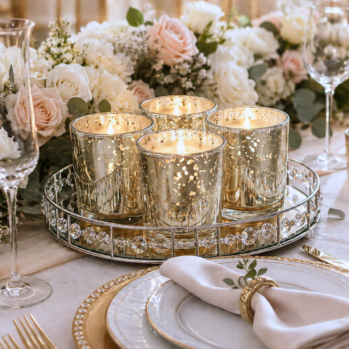Four glowing Metallic Gold Mercury Votive Holder pieces arranged on a mirrored vanity tray