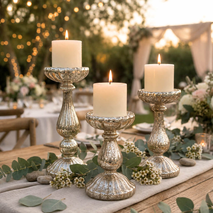Ribbed mercury glass pillar candle holders with lit candles on a decorated wedding table