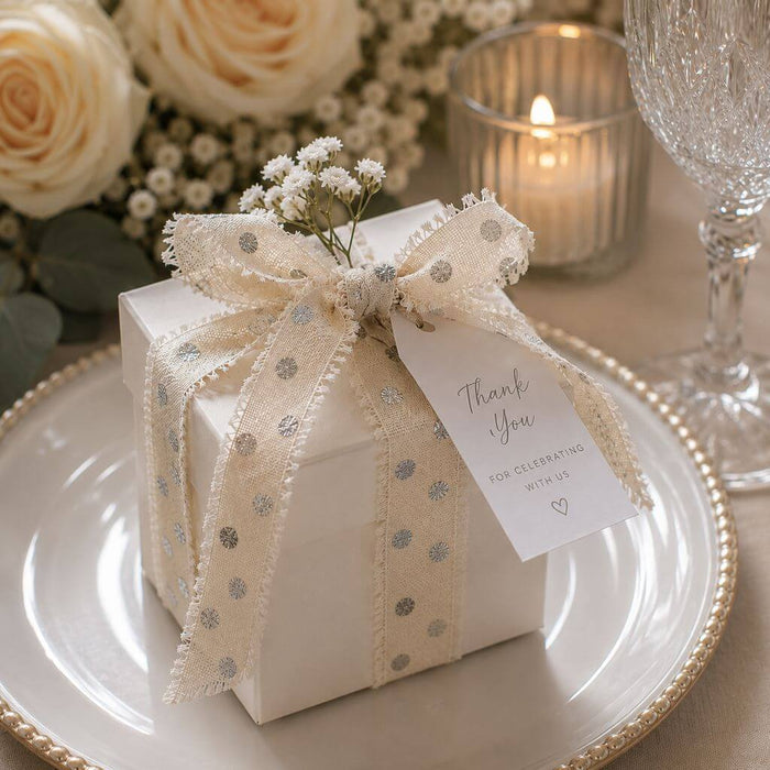 White gift box tied with linen ribbon, flowers, and a thank you tag