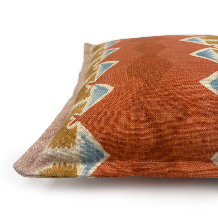 Decorative cushion with geometric pattern in rust, blue and ochre.